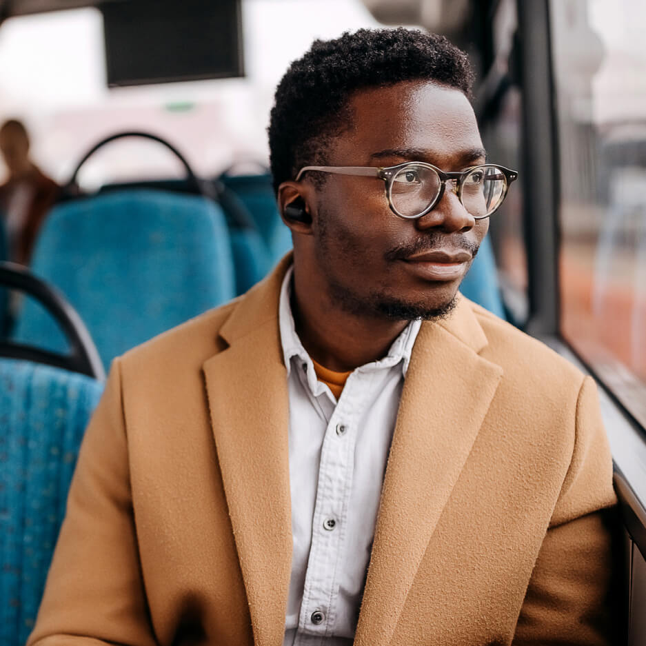 Young man on public bus holding mobile phone while looking out the window